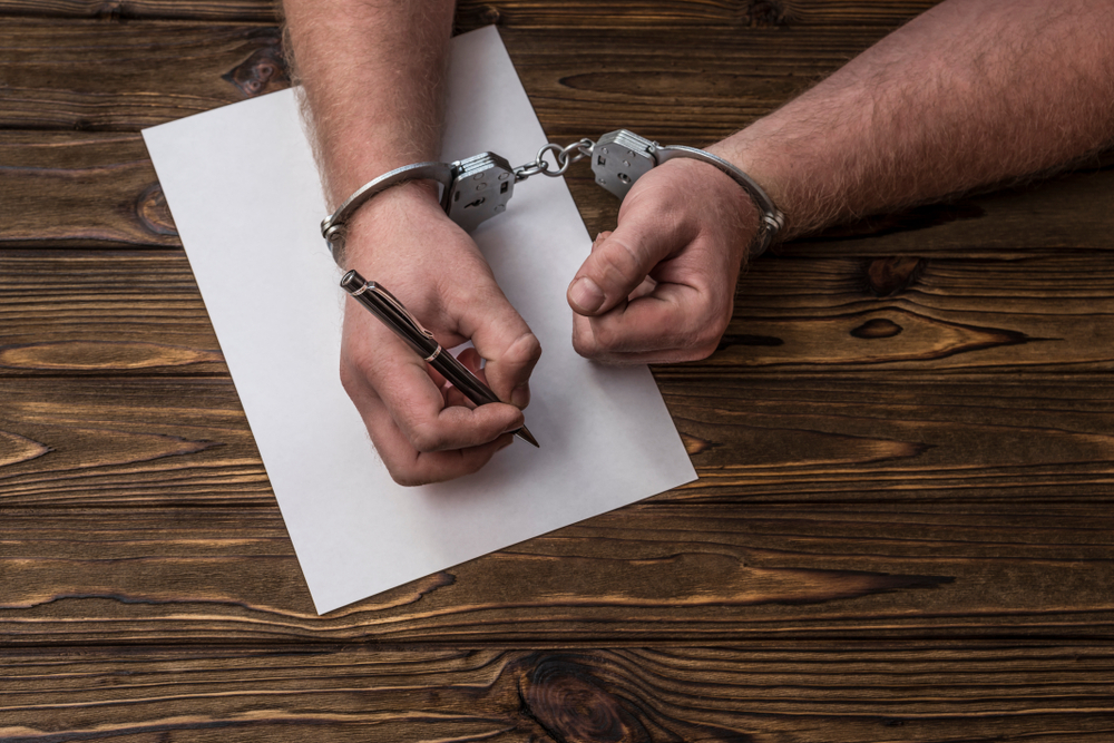 Person in handcuffs signing a document.