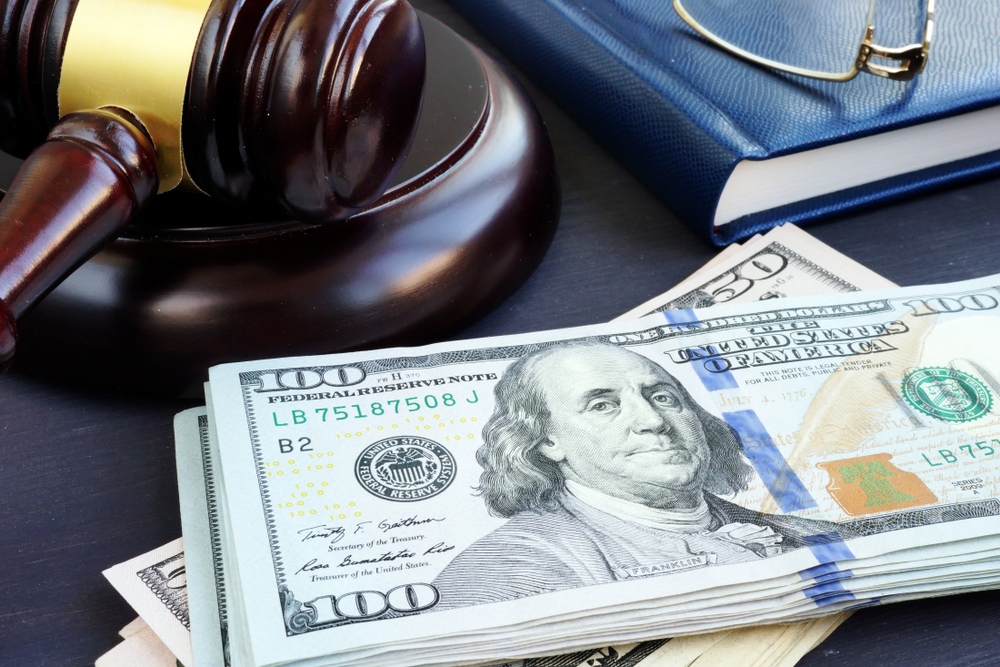 Gavel, book, and glasses placed near a stack of money
