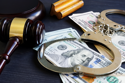 Gavel, money, and open handcuffs on a table